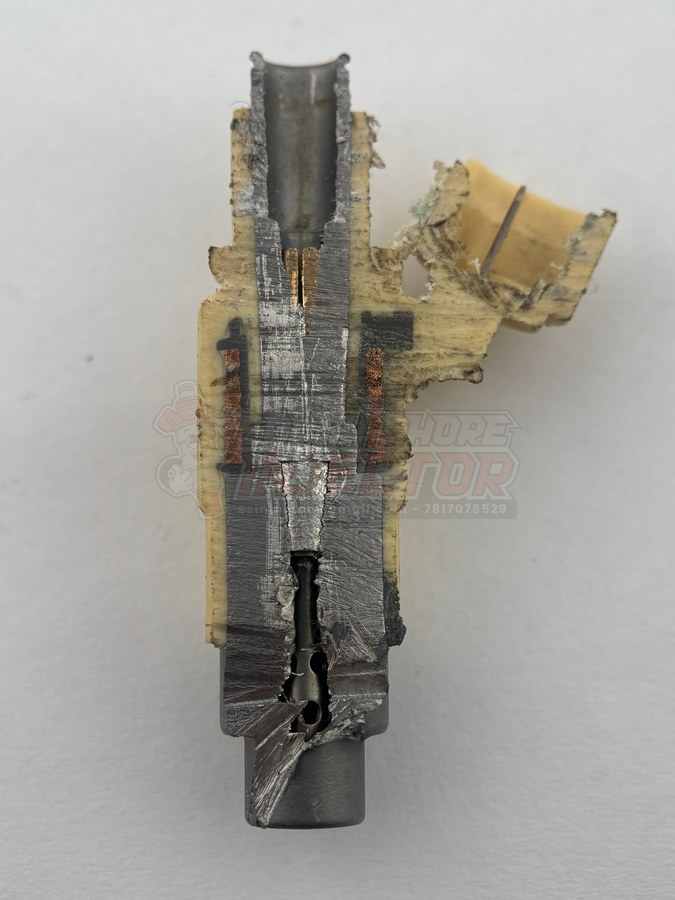 Real fuel injector cut in half lengthwise, showing the internal fuel passage, copper solenoid coil windings, pintle, and nozzle