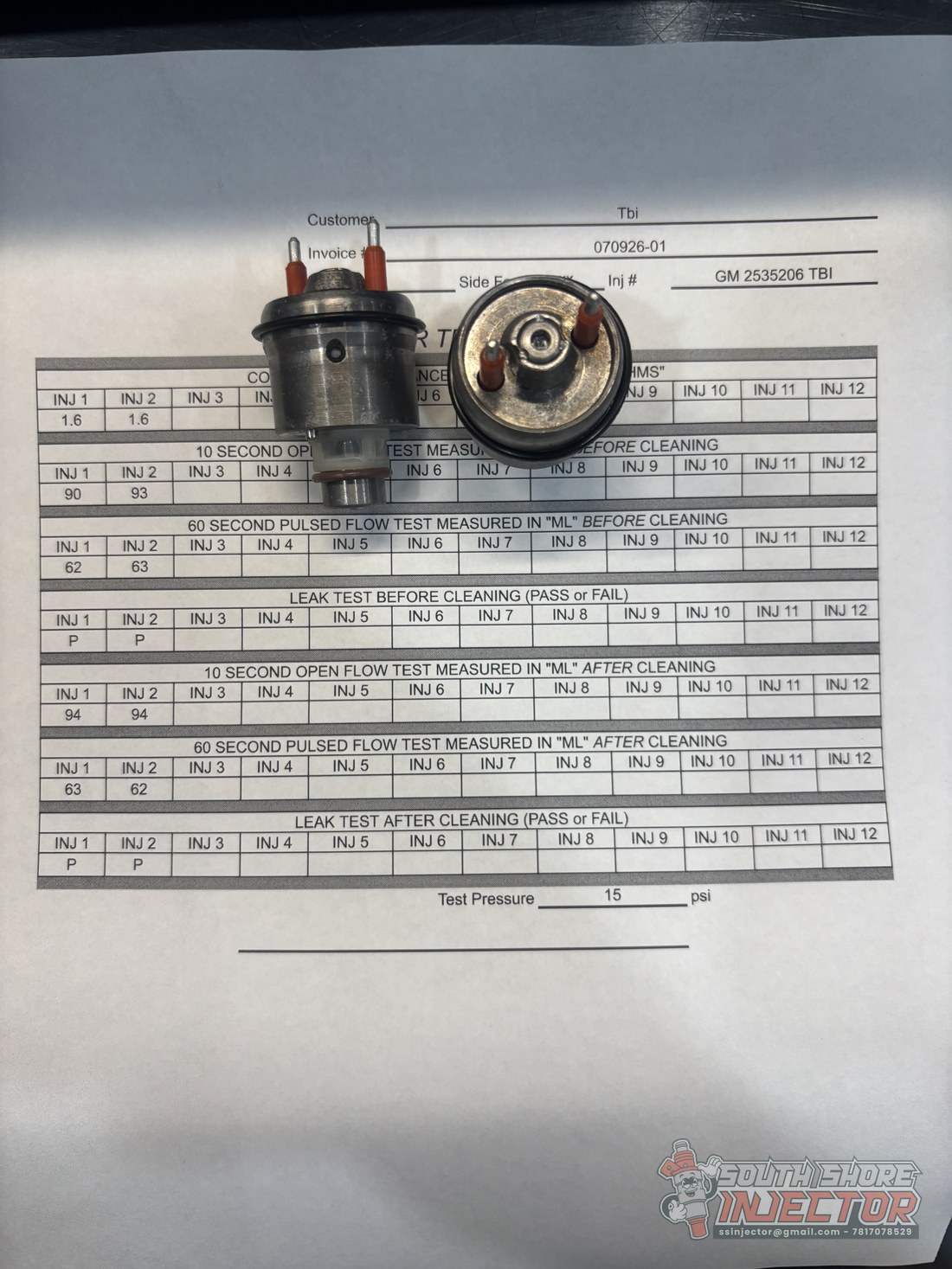 Two cleaned GM TBI injectors sitting on a South Shore Injector performance report showing before and after flow test numbers